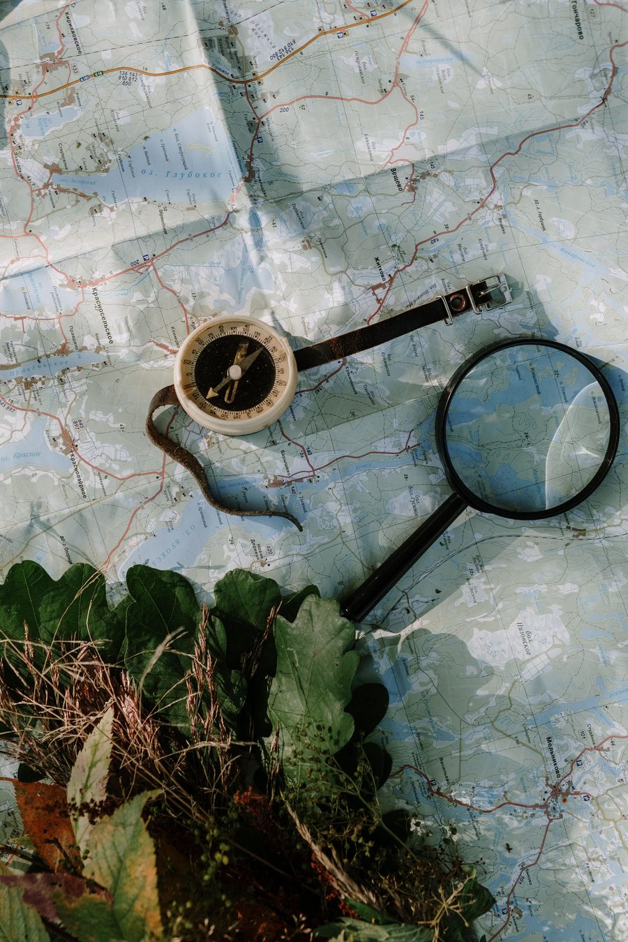 A magnifying glass and compass resting on a map